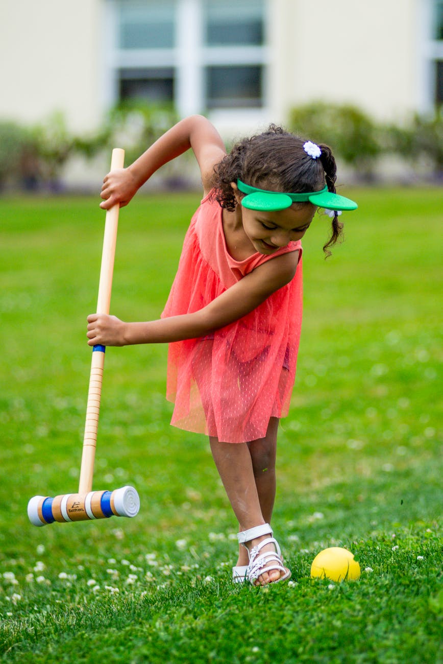 child playing croquet on green grass