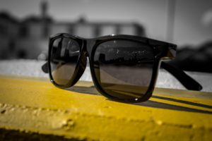 black sunglasses on yellow wooden surface
