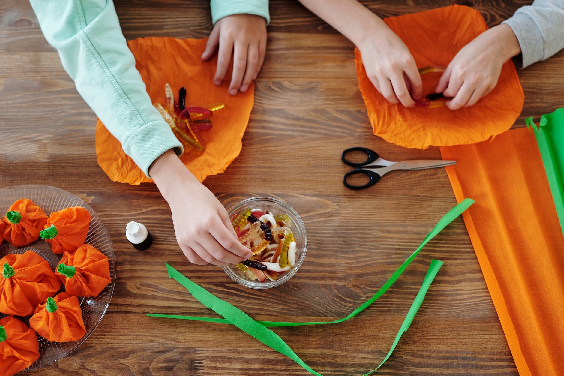 kids wrapping candies in an orange paper