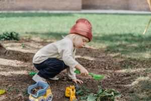 little boy playing with plastic shovel in backyard