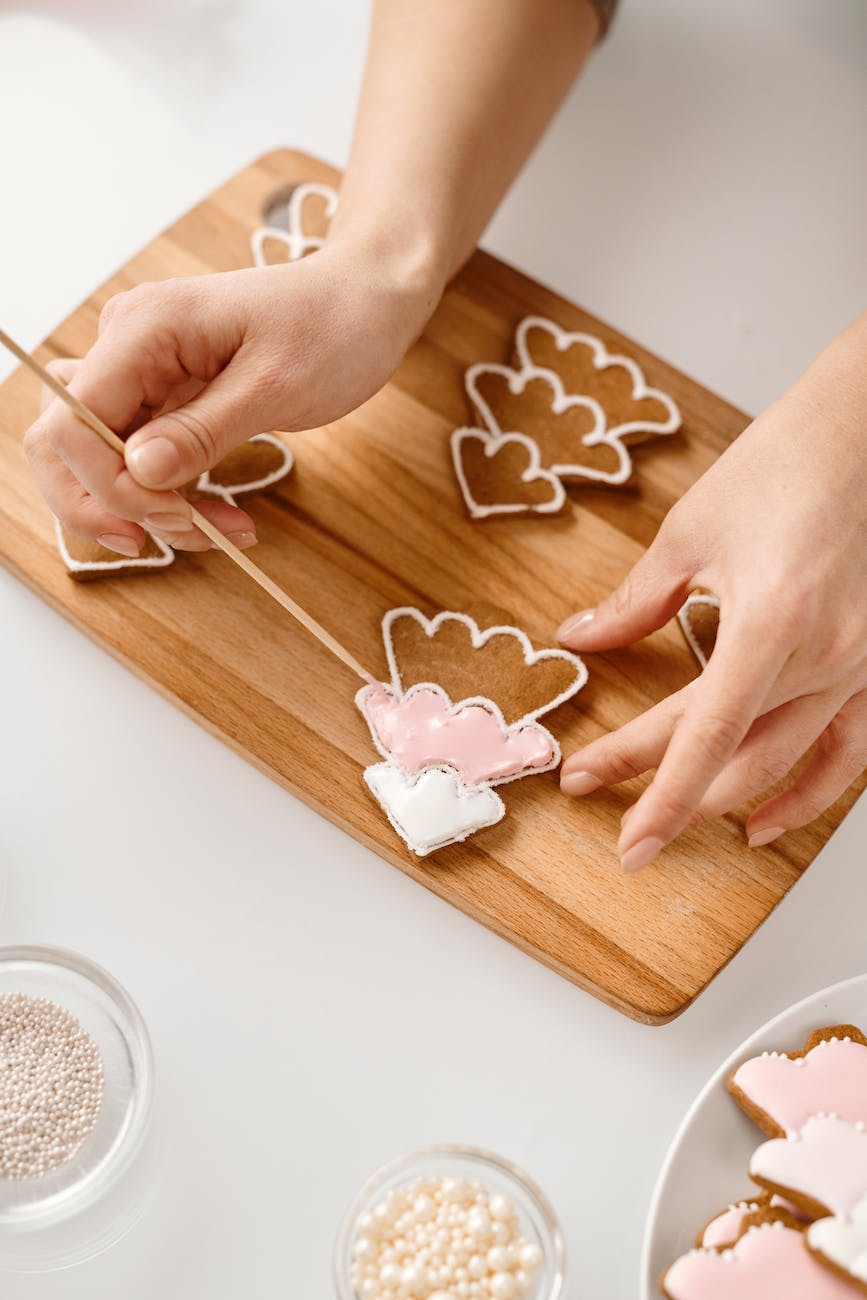 person decorating a christmas tree shaped cookies